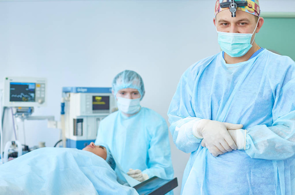 Αρκετοί γιατροί γύρω από ασθενή σε λειτουργία πίνακα κατά την εργασία τους. Ομάδα χειρουργών στην εργασία στο χειρουργείο - Φωτογραφία, εικόνα