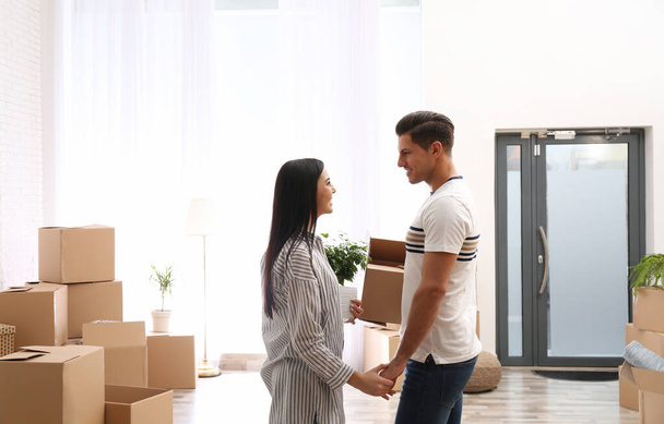 Happy couple in room with cardboard boxes on moving day - Fotoğraf, Görsel