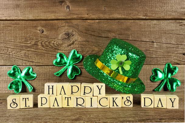 Happy St Patricks Day wooden blocks with shiny shamrocks and leprechaun hat on a wooden background - Фото, изображение