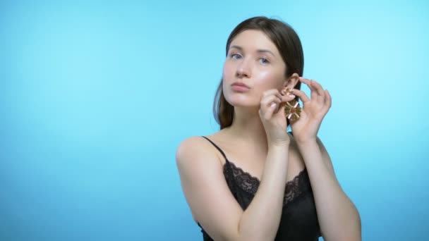 Porträt eines schönen Mädchens. blauer Hintergrund. das Mädchen trägt Ohrringe - Filmmaterial, Video