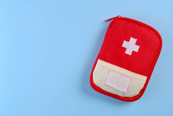 Closed red travel first aid kit pouch on the bright blue background. Photo with a copy space - Fotografie, Obrázek