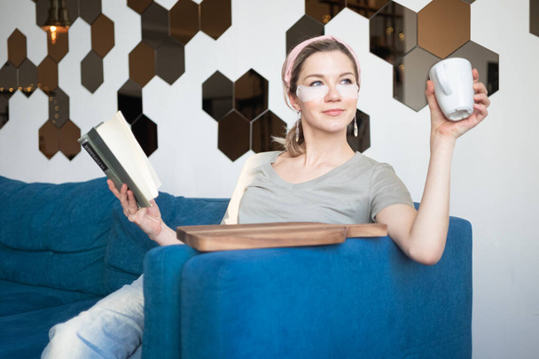 young attractive woman sitting and reading book, drinking coffee. Self care concept - Fotó, kép
