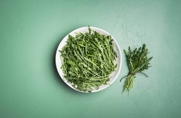 Arugula saláta és arugula köteg a zöld asztalon. Friss fűszernövények  - Fotó, kép