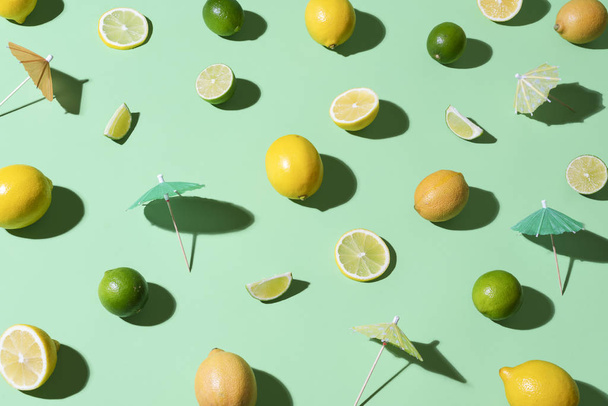 Limes, lemons and cocktail umbrellas. Tropical summer background - 写真・画像