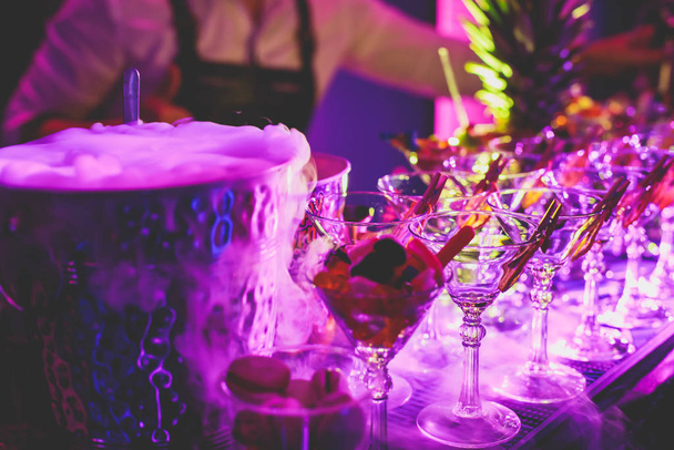 Yemek masasında alkol ayarı, bir partide sıra sıra değişik renkte alkol kokteylleri, martini, votka ve dekore edilmiş buket masasında diğerleri.  - Fotoğraf, Görsel