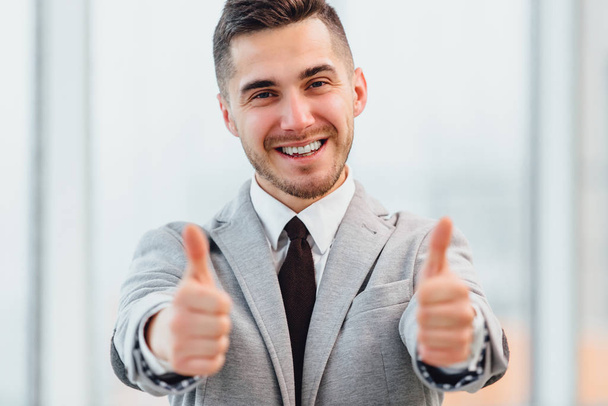 Cropped photo of successful businessman with thumbs up celebrating his victory, smiling at the camera. - Photo, image