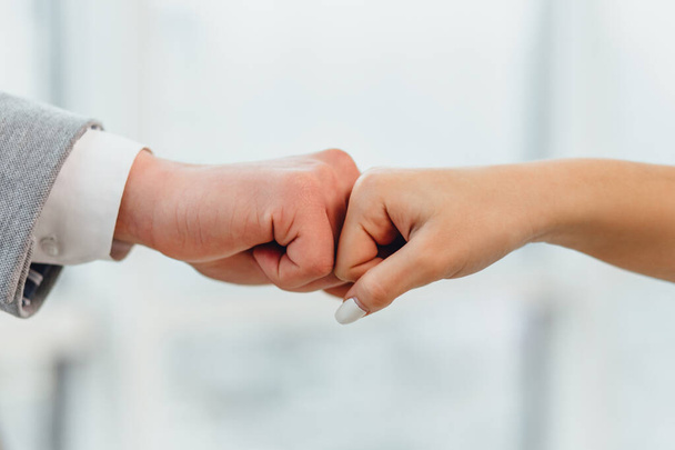 Candid shot of happy successful businesspartners wearing formal clothing and fist-bumping while cheering and congratulating profitable deal. - Foto, Imagen
