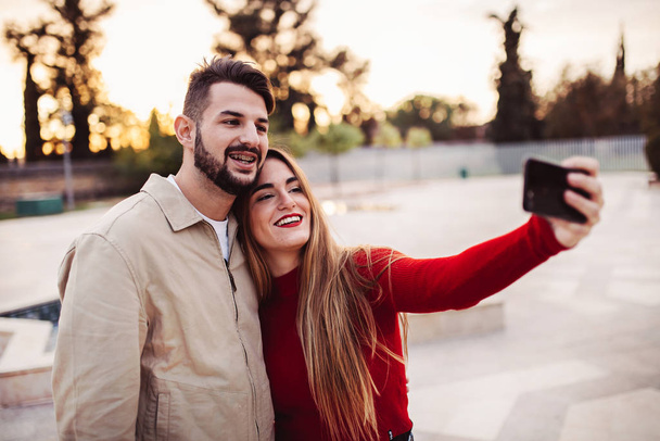boy and girl making a selfie at sunset, lifestyle concept - Фото, зображення