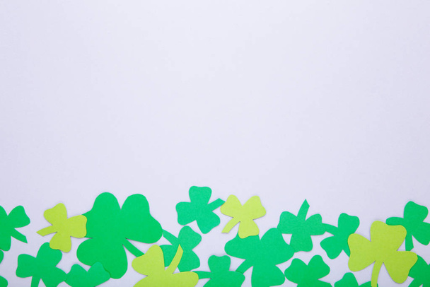 Happy Saint Patrick's of handmade paper clover leaves on grey background. - Photo, image