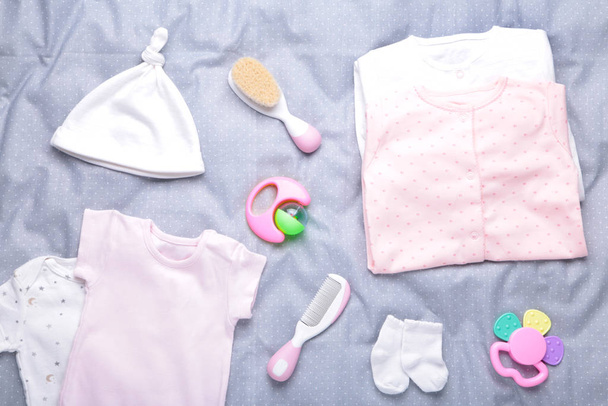 Baby clothes with a shower accessories on a grey background - Фото, изображение