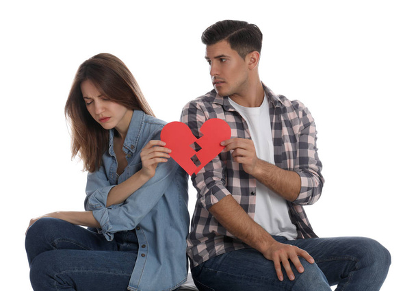 Couple with torn paper heart on white background. Relationship problems - Photo, image