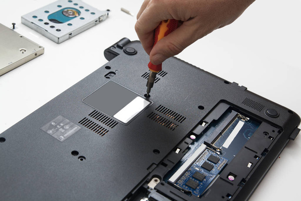 Laptop repair. A wizard with a screwdriver disassembles the lapt - Photo, Image