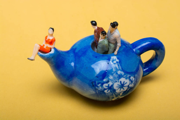 Grupa miniaturowych postaci ludzi stojących w czajniku - Zdjęcie, obraz