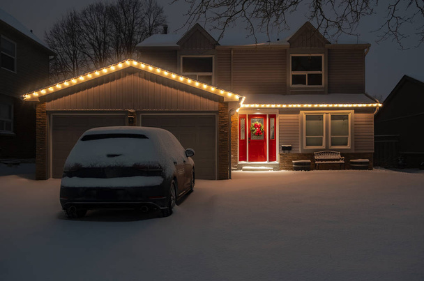Scatto notturno di una casa indipendente di periferia con una porta rossa tutta accesa con le luci di Natale
 - Foto, immagini