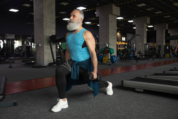 Bearded Senior man in sports clothing in gym working out with weights. - Fotoğraf, Görsel