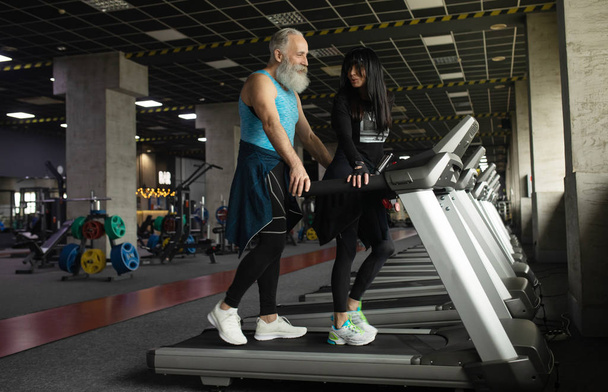 Χαριτωμένο χαμογελαστό ζευγάρι ηλικιωμένων άσκηση στο γυμναστήριο. - Φωτογραφία, εικόνα