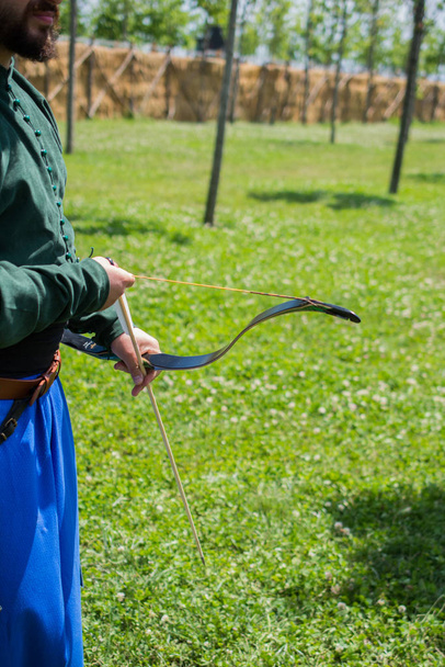 Лучник в традиционной одежде стреляет стрелой
 - Фото, изображение