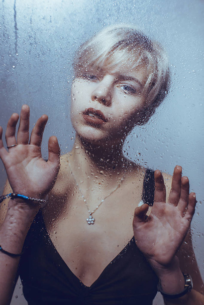 The girl stands at the wet glass - Φωτογραφία, εικόνα