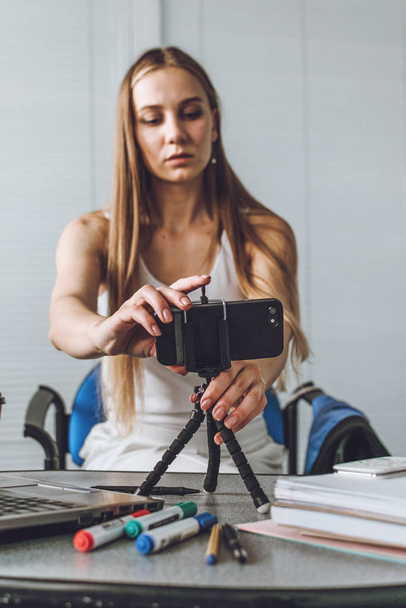 Νεαρή γυναίκα μιλάει μπροστά στην κάμερα για το vlog ως blogger. Καυκάσια επιχειρηματίας που δουλεύει, μαγνητοσκοπεί μαθήματα στο γραφείο. Κερδίστε επιπλέον χρήματα, Πλευρική σπουδή, χρήματα κάνοντας, μετατρέποντας τα χόμπι σε μετρητά - Φωτογραφία, εικόνα