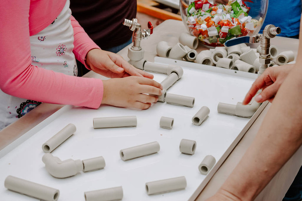 Мероприятия для детей в помещении, игры и творческая концепция. Дети играют с веселыми тоннелями и трубами набор, пластиковый блок комплект. Заполненные весельем водопроводные трубы для создания поворотных конструкций
 - Фото, изображение