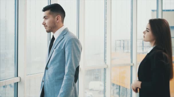 Man is looking out the panoramic window. Acquaintance of two business people in office, on the panoramic blurred background. Close up. Copy space. 4K. - Filmati, video