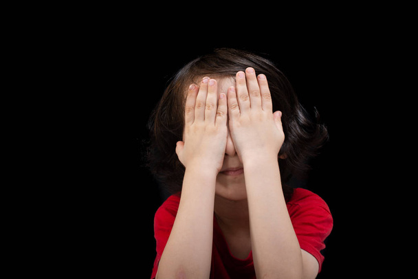 Vista de niño lindo reflexivo que cubre sus ojos con su mano
 - Foto, imagen
