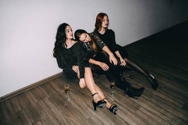 After party, jet set, clubbing, nightlife concept. Tired girls with glasses of champagne sit on the floor after celebrating party - Photo, Image