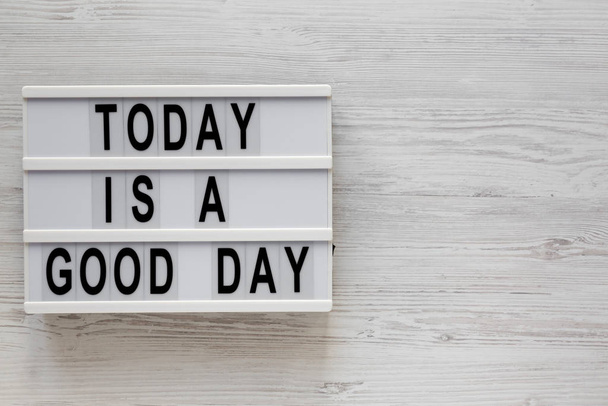 "Σήμερα είναι μια καλή μέρα" λέξεις σε ένα lightbox σε ένα λευκό ξύλινο πίσω μέρος - Φωτογραφία, εικόνα
