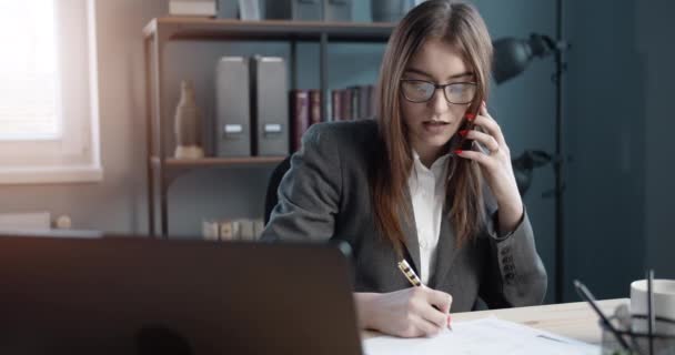 Female manager taking notes during conversation on phone - Filmagem, Vídeo