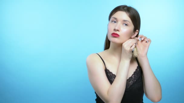 portrait of a beautiful girl. blue background. the girl wears earrings - Materiał filmowy, wideo