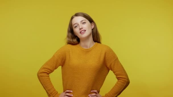 Confident rich girl in casual outfit looking arrogantly at camera while dollar bills falling around, proud of big money and wealthy life, sudden lottery gain. studio shot isolated on yellow background - Video