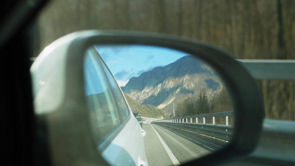 snowy mountains reflected in the rearview mirror while the vehicle is in motion - Foto, afbeelding