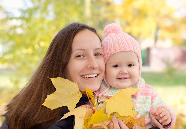 Mom and daughter with leaves - Foto, afbeelding