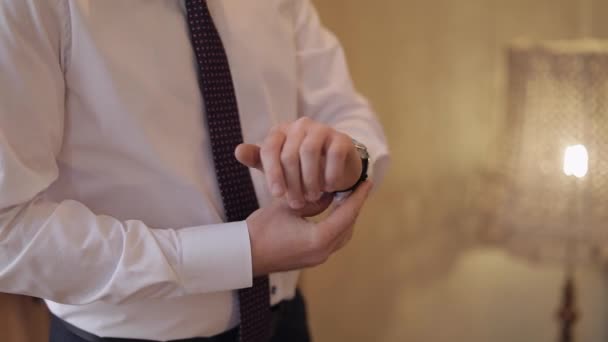 ハンサムな新郎は彼の時計を修正します。白いシャツ結婚式の朝実業家 - 映像、動画