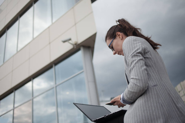 Young ambitious woman with a laptop in her hands on the background of the business center. - Zdjęcie, obraz