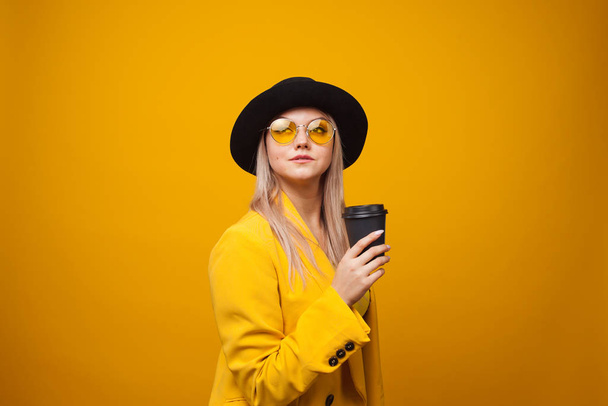 Take-away coffee. Stylish trendy young woman in bright clothes on a yellow background. - Fotoğraf, Görsel