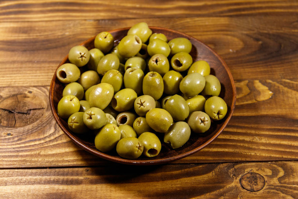Plate with green olives on wooden table - Photo, Image