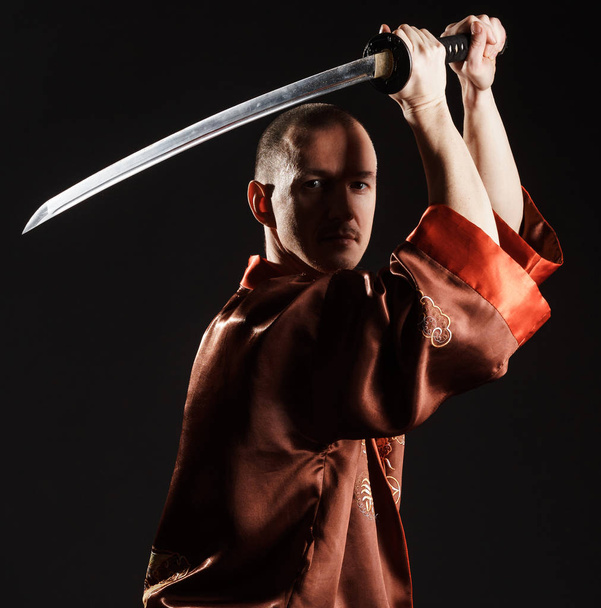 Man in chinese costume with sword studio portrait - Foto, Imagen