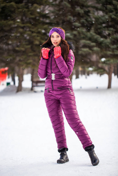 Portrait of a young beautiful woman in a ski suit posing in wint - Fotó, kép