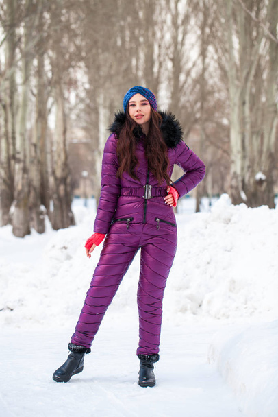 Portrait of a young beautiful woman in a ski suit posing in wint - Fotó, kép
