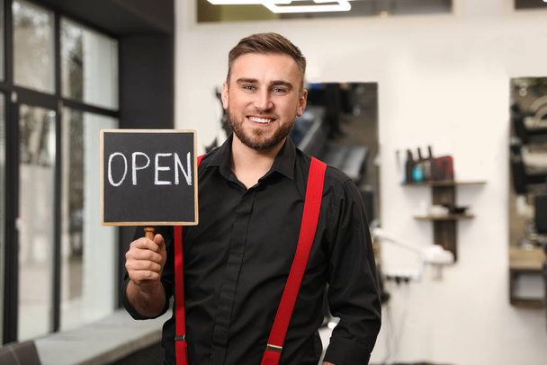 Young business owner holding OPEN sign in his barber shop - Fotografie, Obrázek