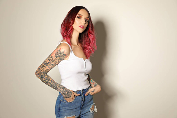 Beautiful woman with tattoos on arms against light background - Zdjęcie, obraz
