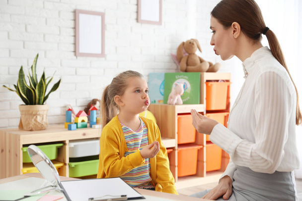 Speech therapist working with little girl in office - Фото, зображення