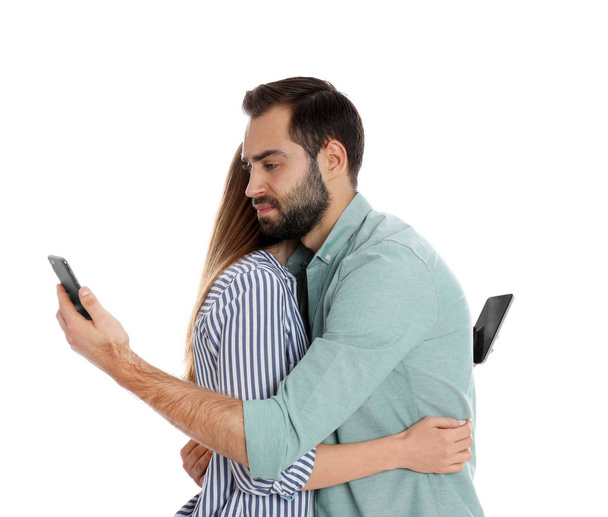 Couple addicted to smartphones hugging on white background. Relationship problems - Foto, imagen