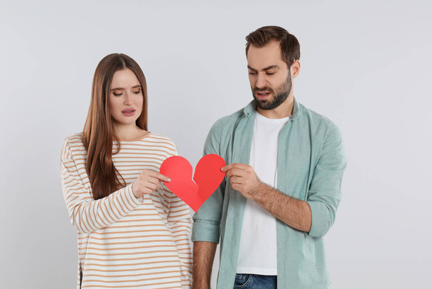 Couple tearing paper heart on light  background. Relationship problems - Fotó, kép