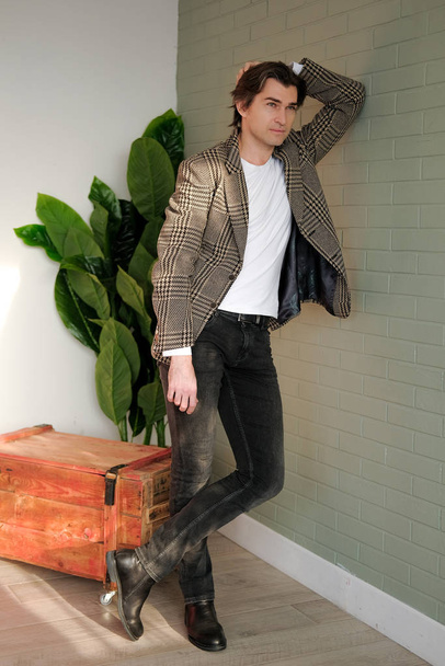 Tall handsome man standing next to grey wall and wooden box - Foto, Imagem