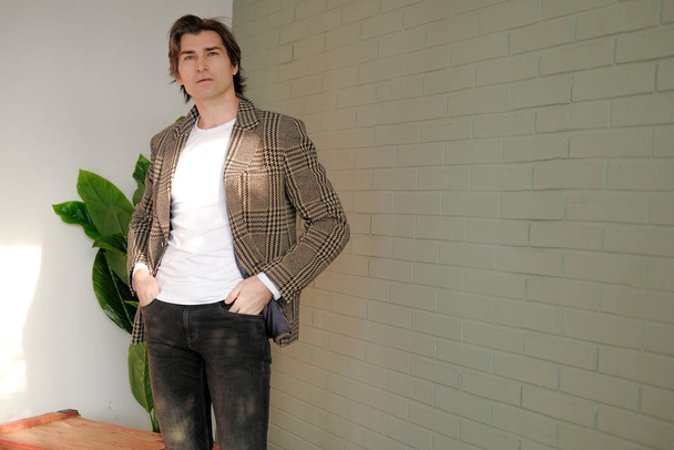 Tall handsome man standing next to grey wall - Fotó, kép