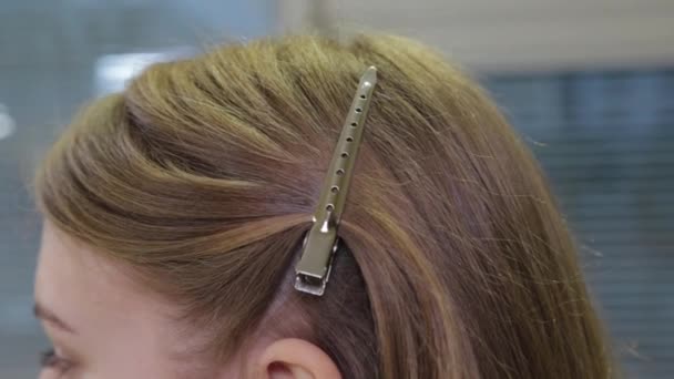 Beautiful girl with a hairpin in her hair in a beauty salon - Footage, Video