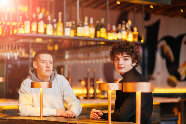Δύο νεαροί φίλοι με γένια τσακώνονται σε μια καφετέρια. - Φωτογραφία, εικόνα