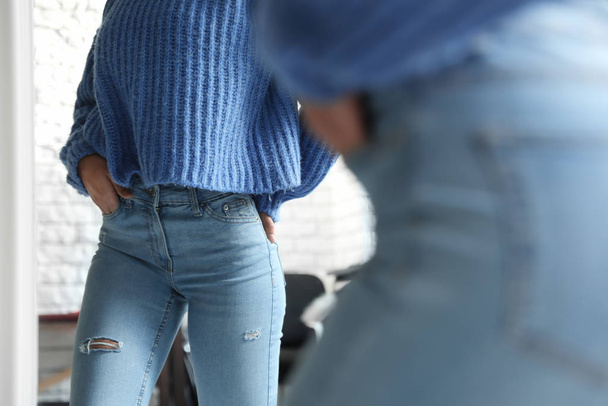 Woman wearing jeans near mirror indoors, closeup - Fotoğraf, Görsel